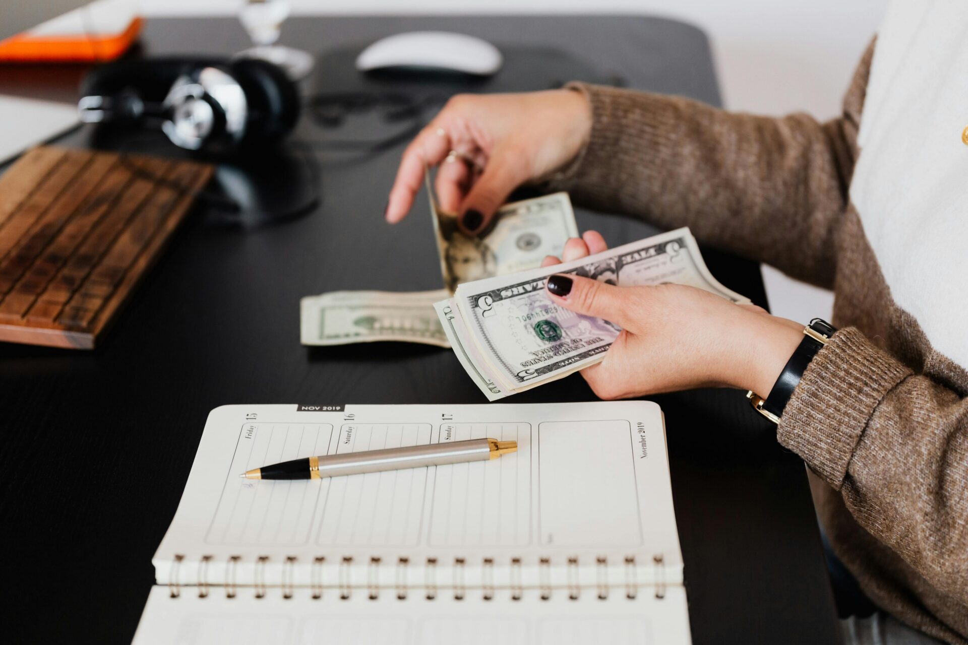 Business owner reviewing cash flow and business loan fees while counting cash at an office desk.
